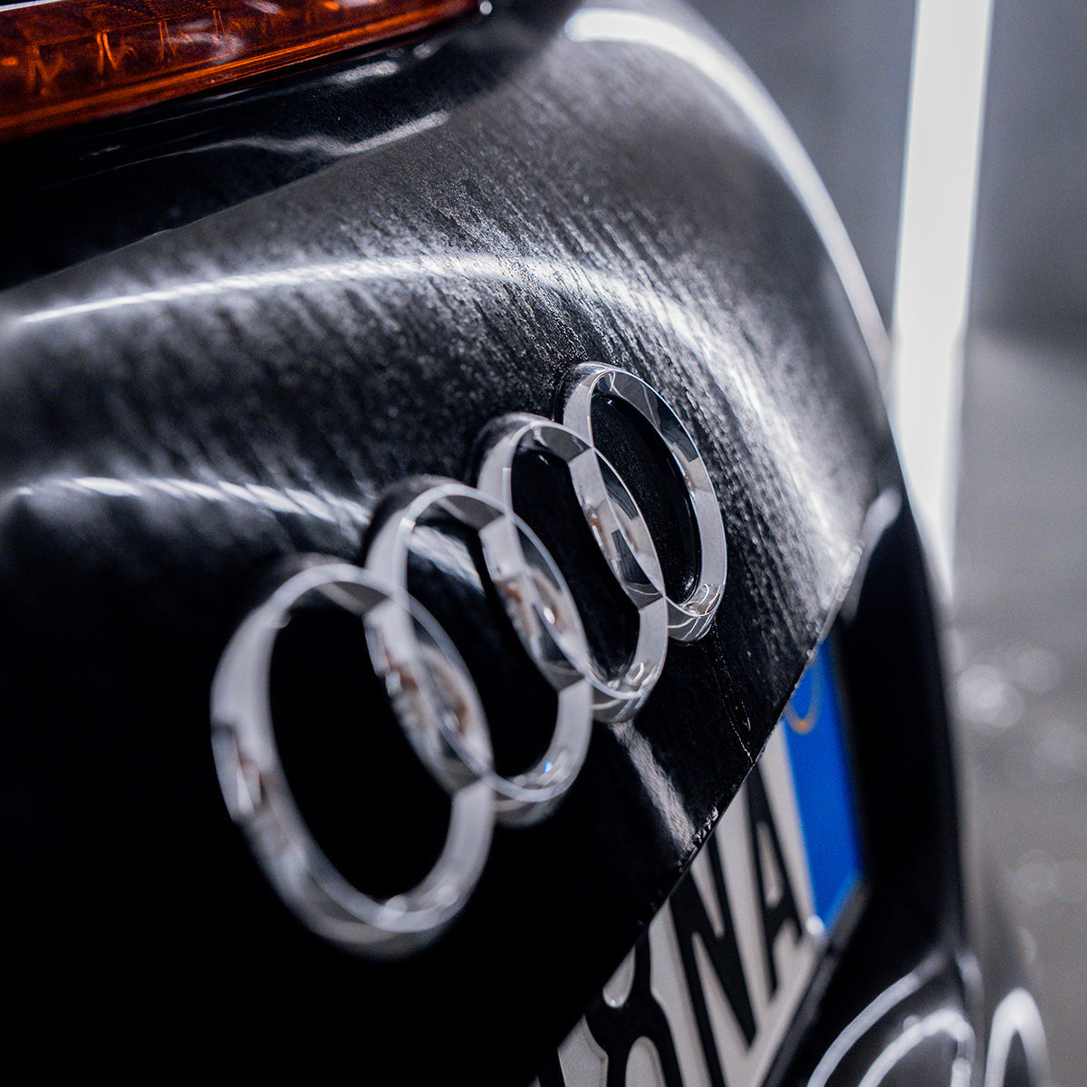Close-up of Audi logo on a car&#39;s side panel.