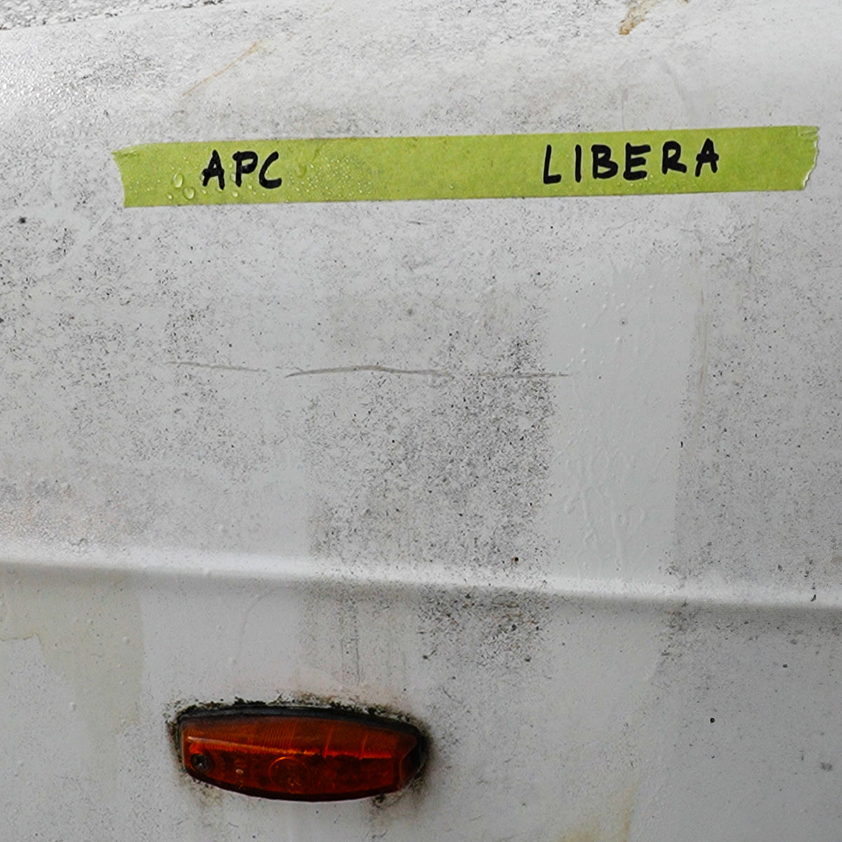 White surface with green tape labeled &#39;APC&#39; and &#39;LIBERA&#39;, and a red light below.