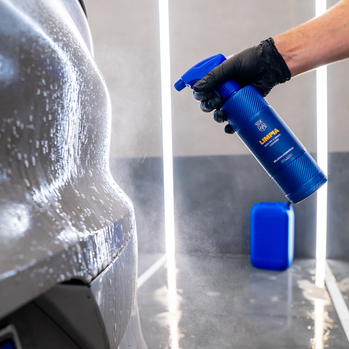 Person using a blue spray bottle labeled &#39;Liqui Moly&#39; to clean a car.