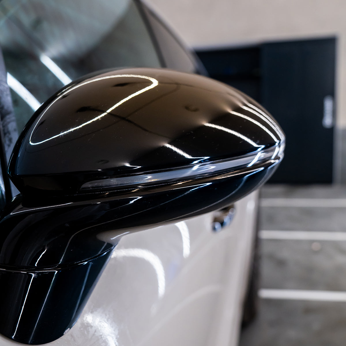 Close-up of a car&#39;s black side mirror with a blurred background