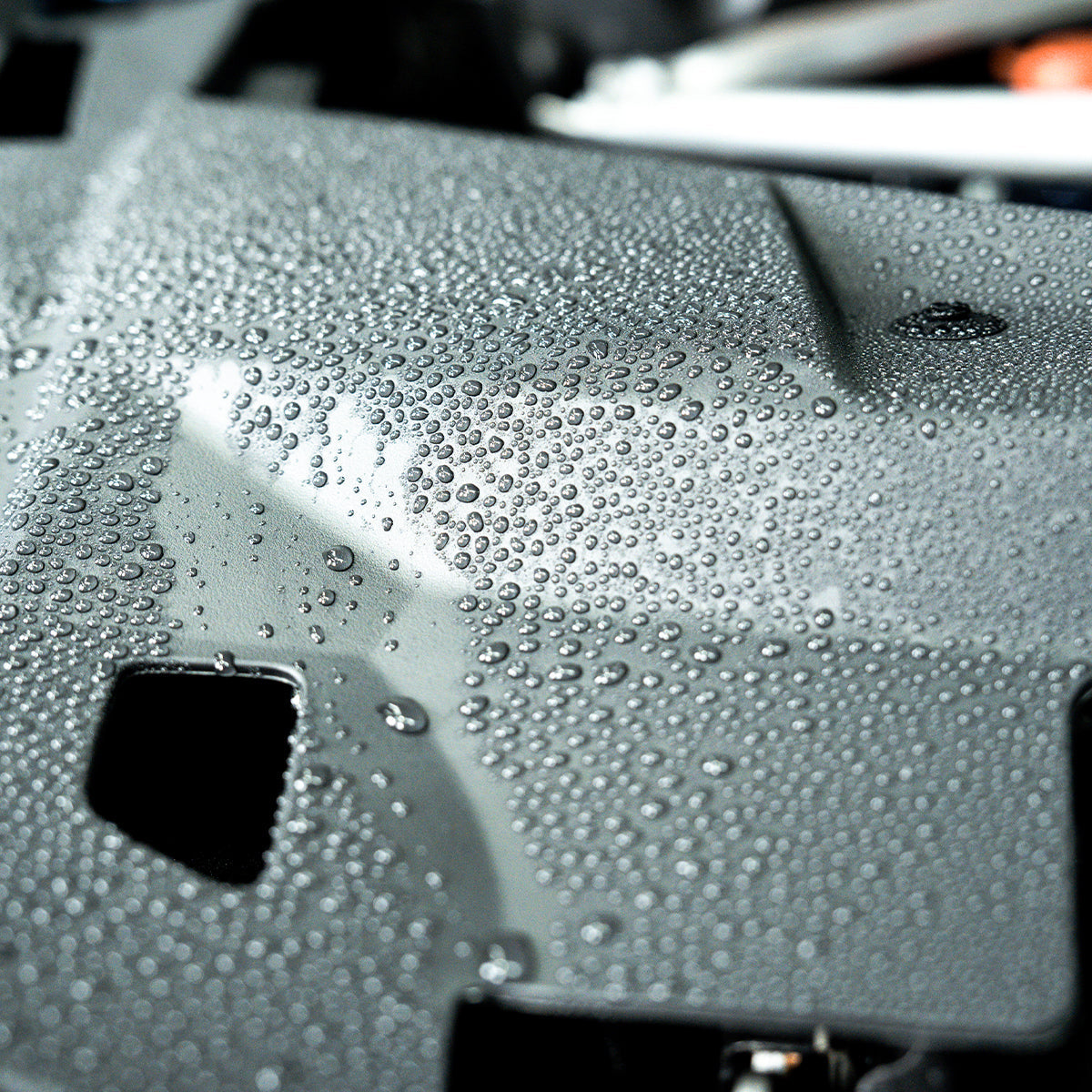 Close-up of a car&#39;s windshield with water droplets on a blurred background