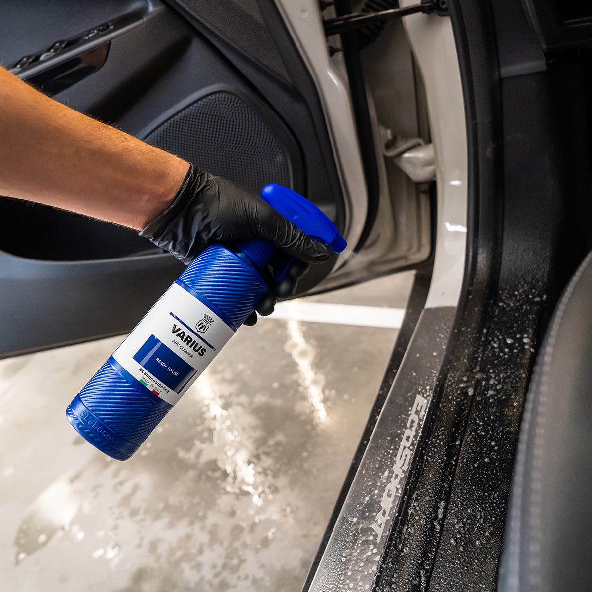 Person cleaning car interior with a spray bottle labeled &#39;Varius&#39;.