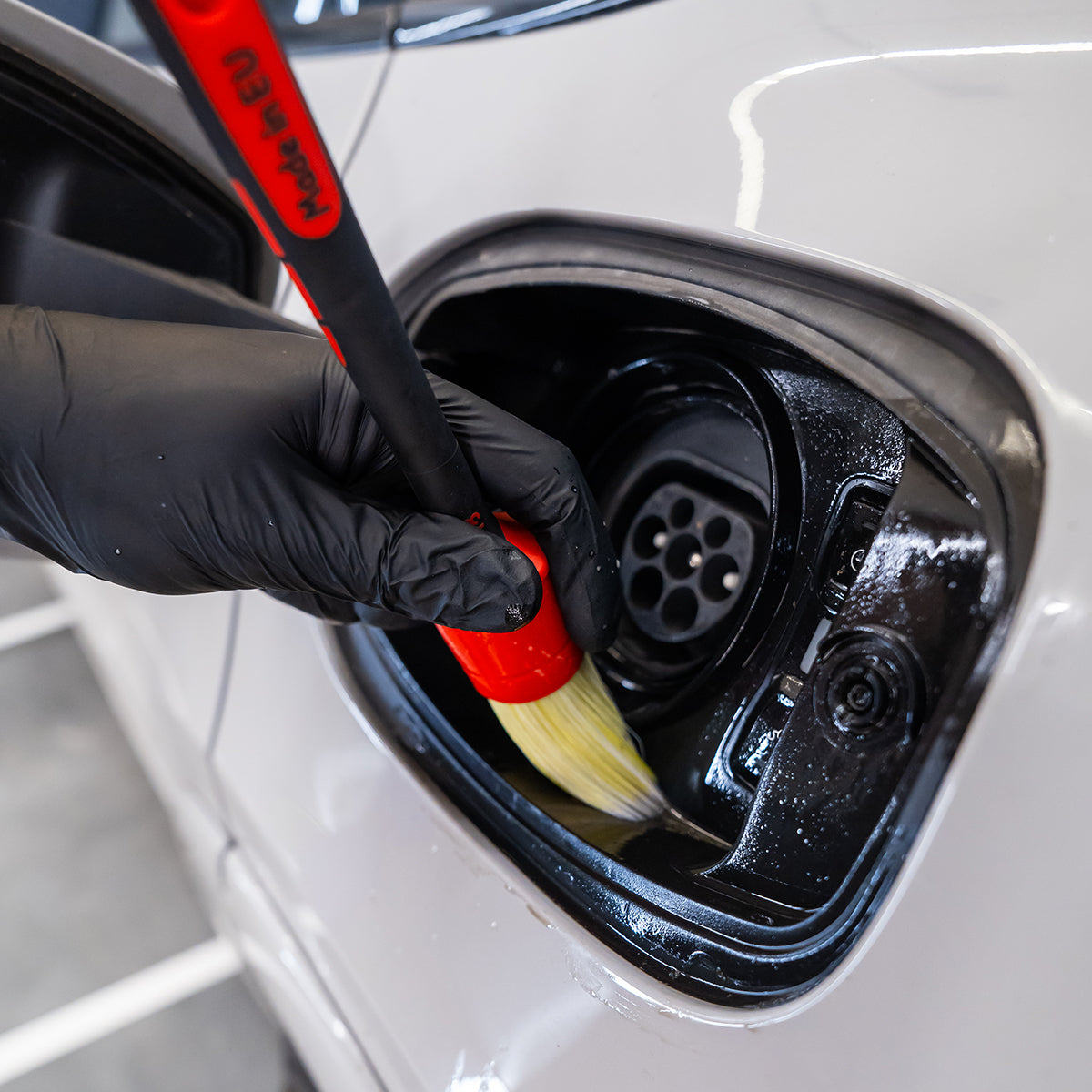 Cleaning a car&#39;s charging port with a brush and black glove