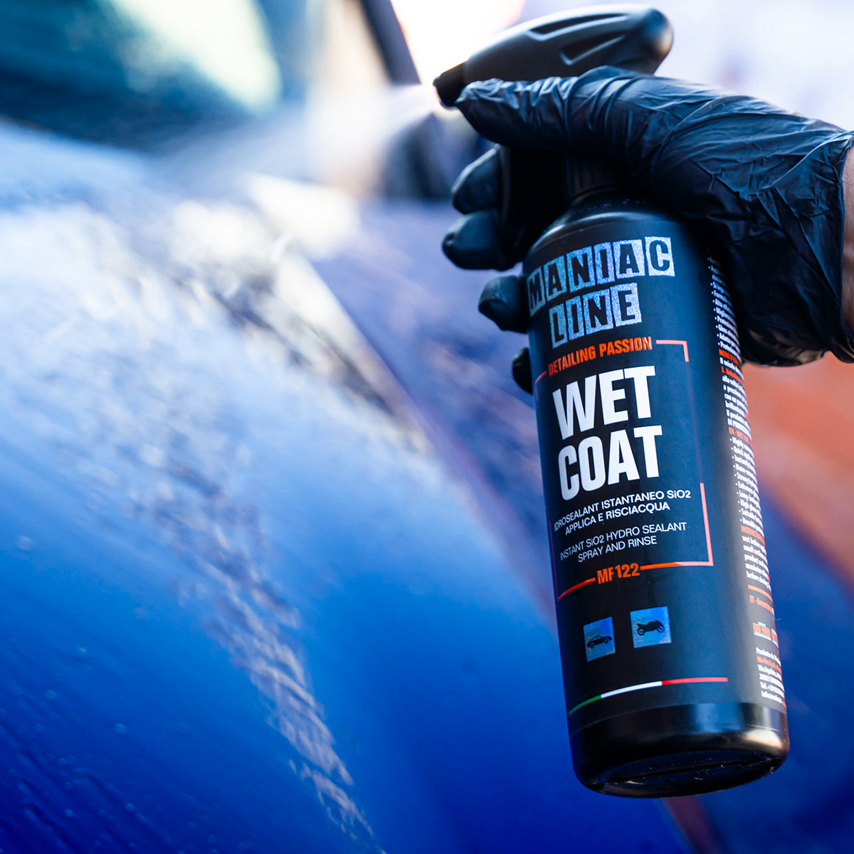 Hand holding a &#39;Maniac Line Wet Coat&#39; can near a car